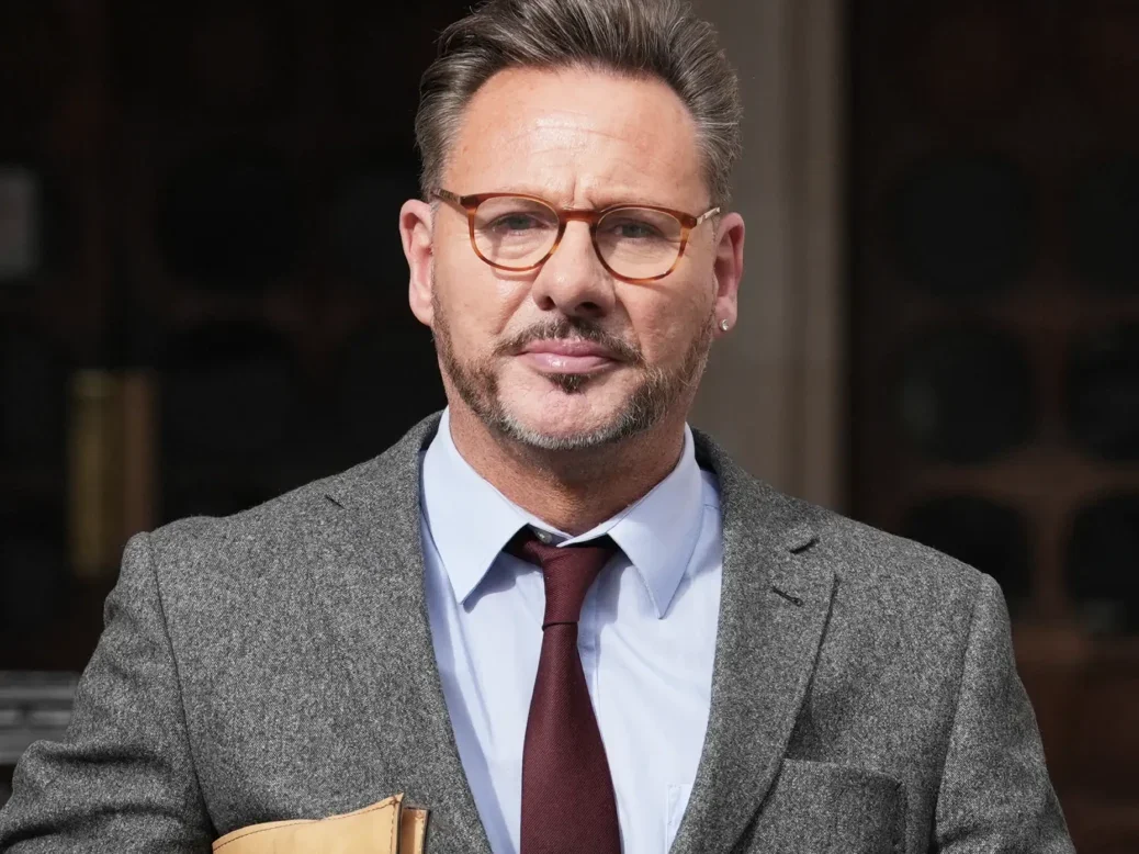 Picture shows Glenn Mulcaire outside a court building dressed in a suit and holding a document folder